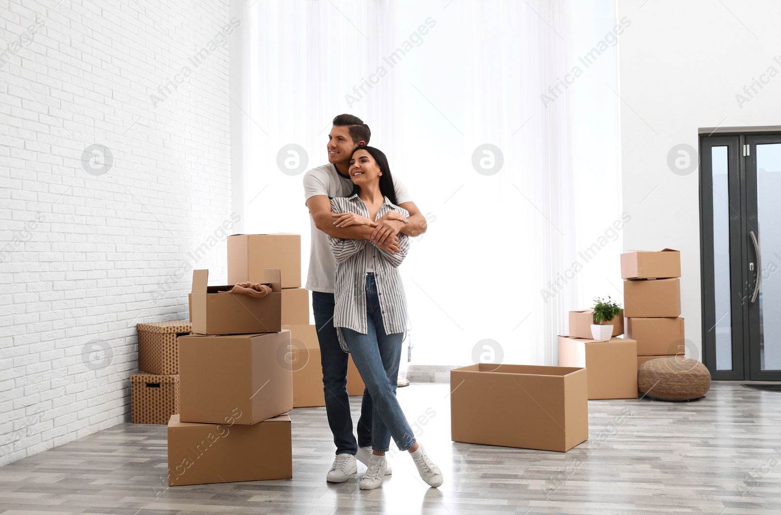 Photo of Happy couple in room with cardboard boxes on moving day