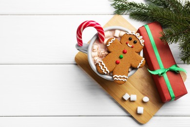 Photo of Tasty homemade Christmas cookie, gift and hot chocolate with marshmallows on white wooden table, top view. Space for text