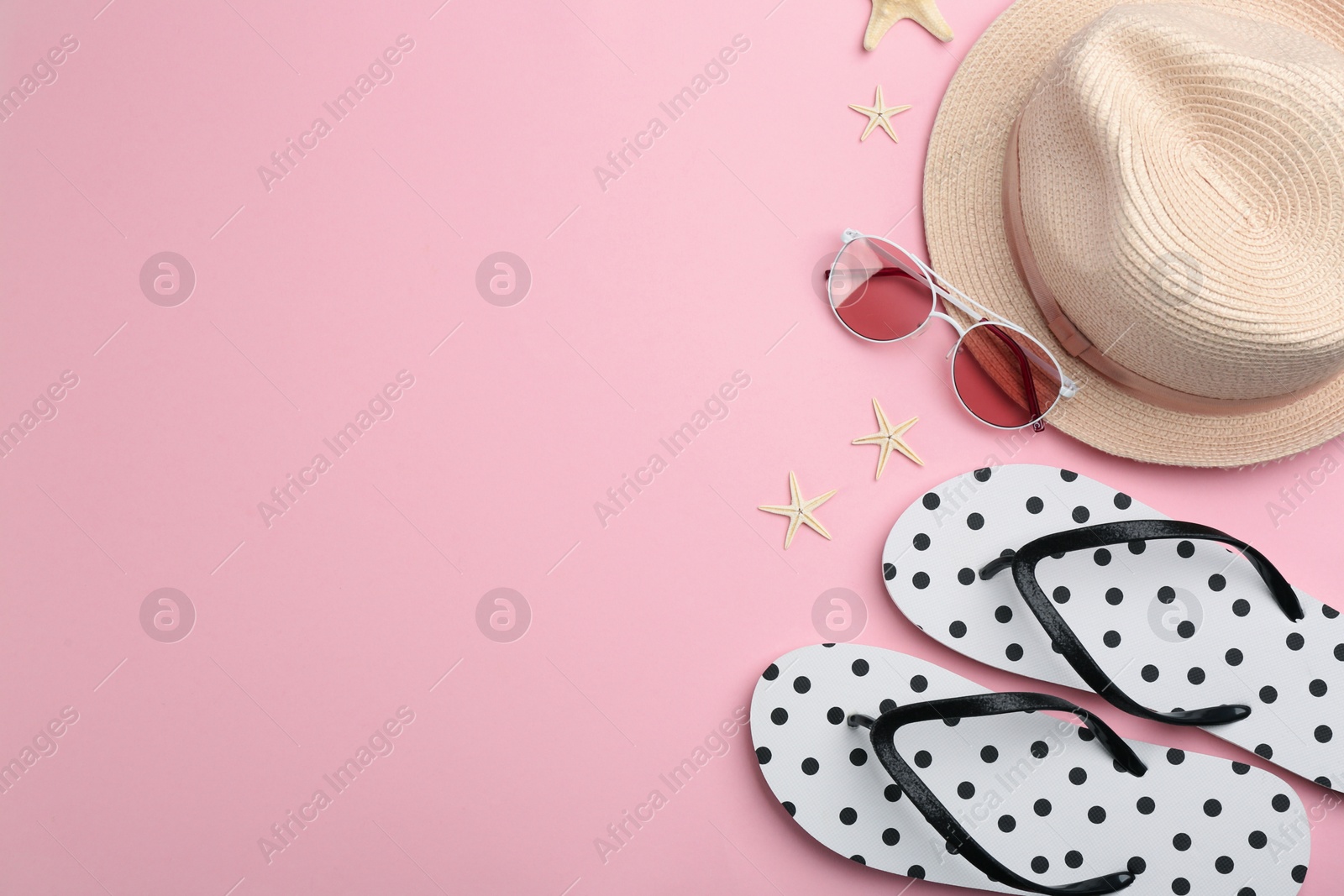 Photo of Flat lay composition with flip flops and beach accessories on pink background. Space for text