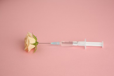 Photo of Medical syringe and beautiful rose on light pink background, above view