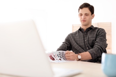 Portrait of confident young man with  laptop at table