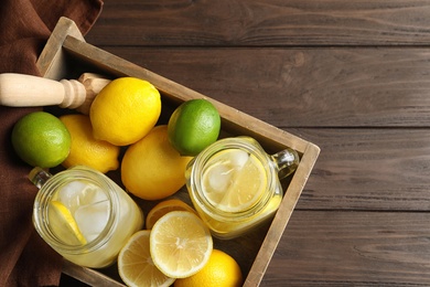 Photo of Mason jars with natural lemonade in wooden crate, top view