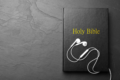 Bible and earphones on black background, top view with space for text. Religious audiobook