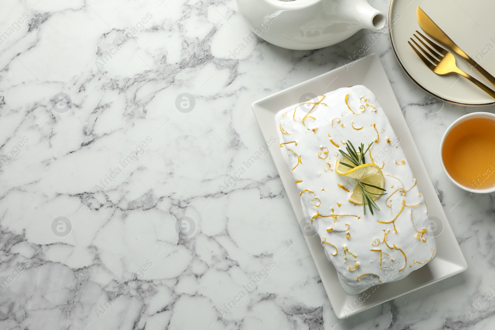 Photo of Tasty lemon cake with glaze served on white marble table, flat lay. Space for text