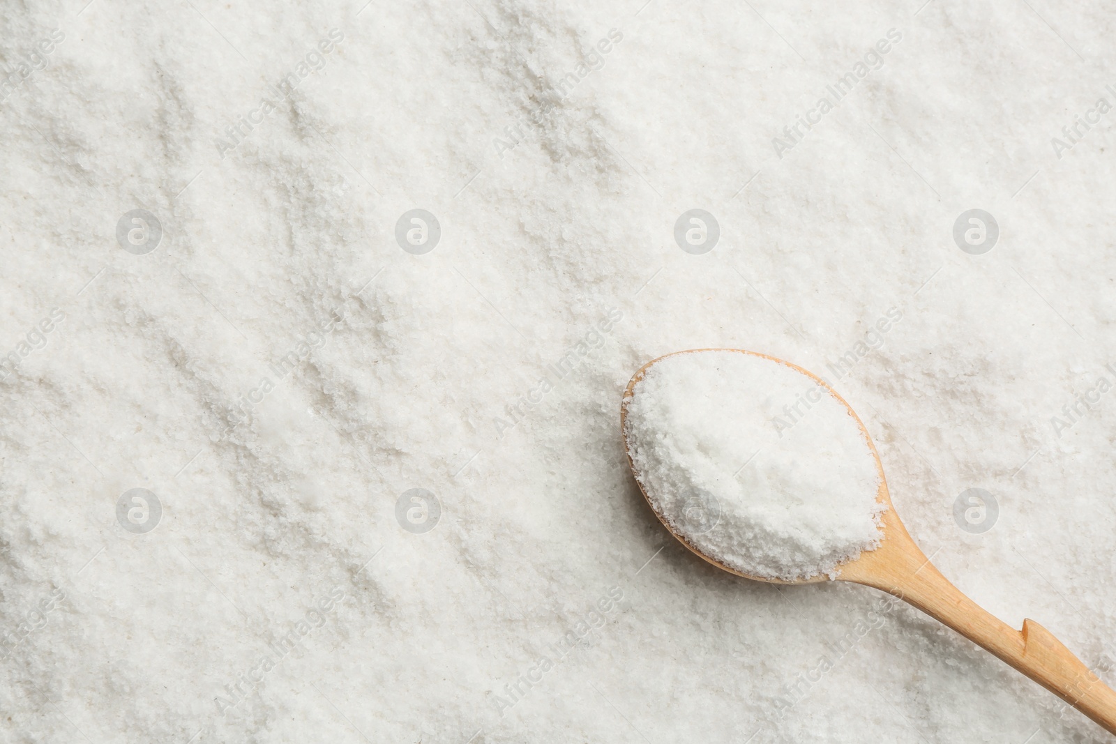 Photo of Natural salt and wooden spoon, top view. Space for text