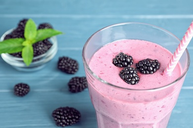 Photo of Delicious blackberry smoothie in glass on blue wooden table, closeup
