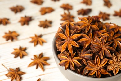 Photo of Many aromatic anise stars on white wooden table, closeup
