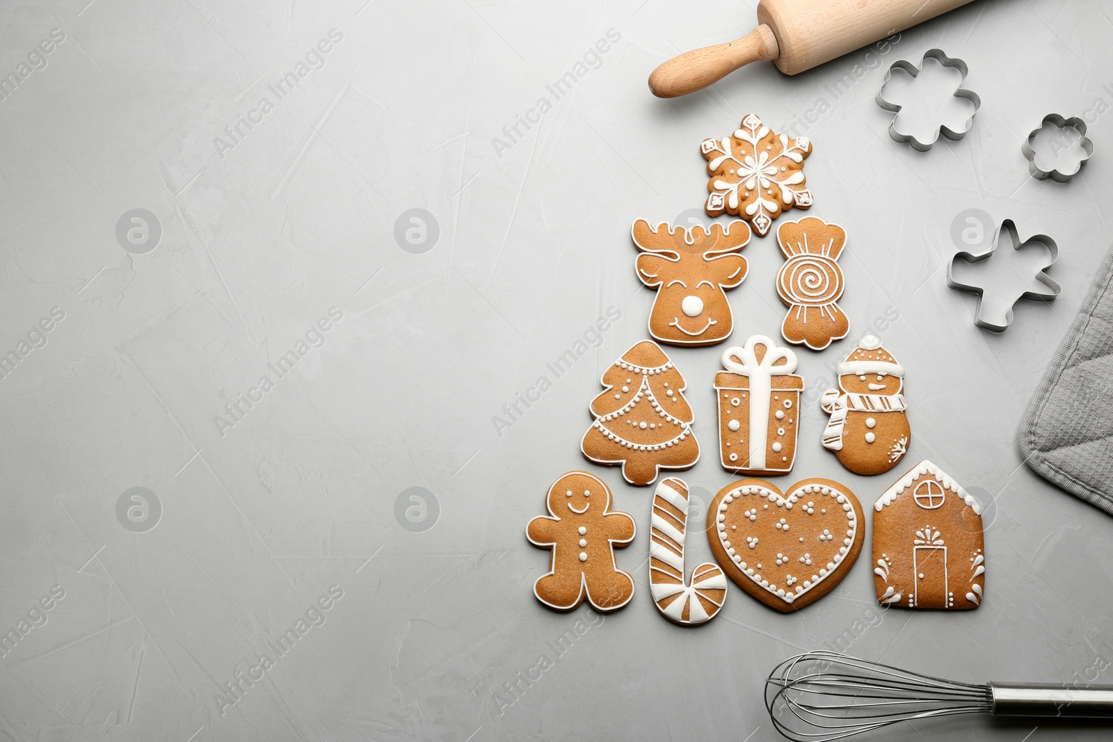 Photo of Kitchen utensils near Christmas tree shape made of delicious gingerbread cookies on light table, flat lay. Space for text