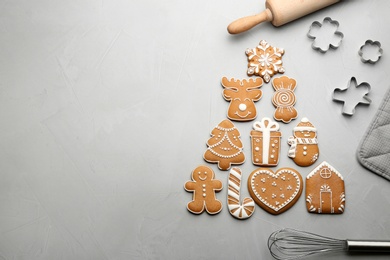 Kitchen utensils near Christmas tree shape made of delicious gingerbread cookies on light table, flat lay. Space for text