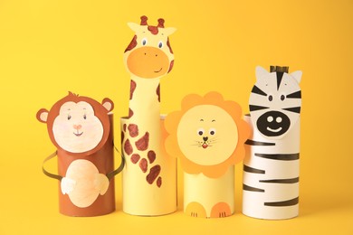 Photo of Toy monkey, giraffe, lion and zebra made from toilet paper hubs on yellow background. Children's handmade ideas
