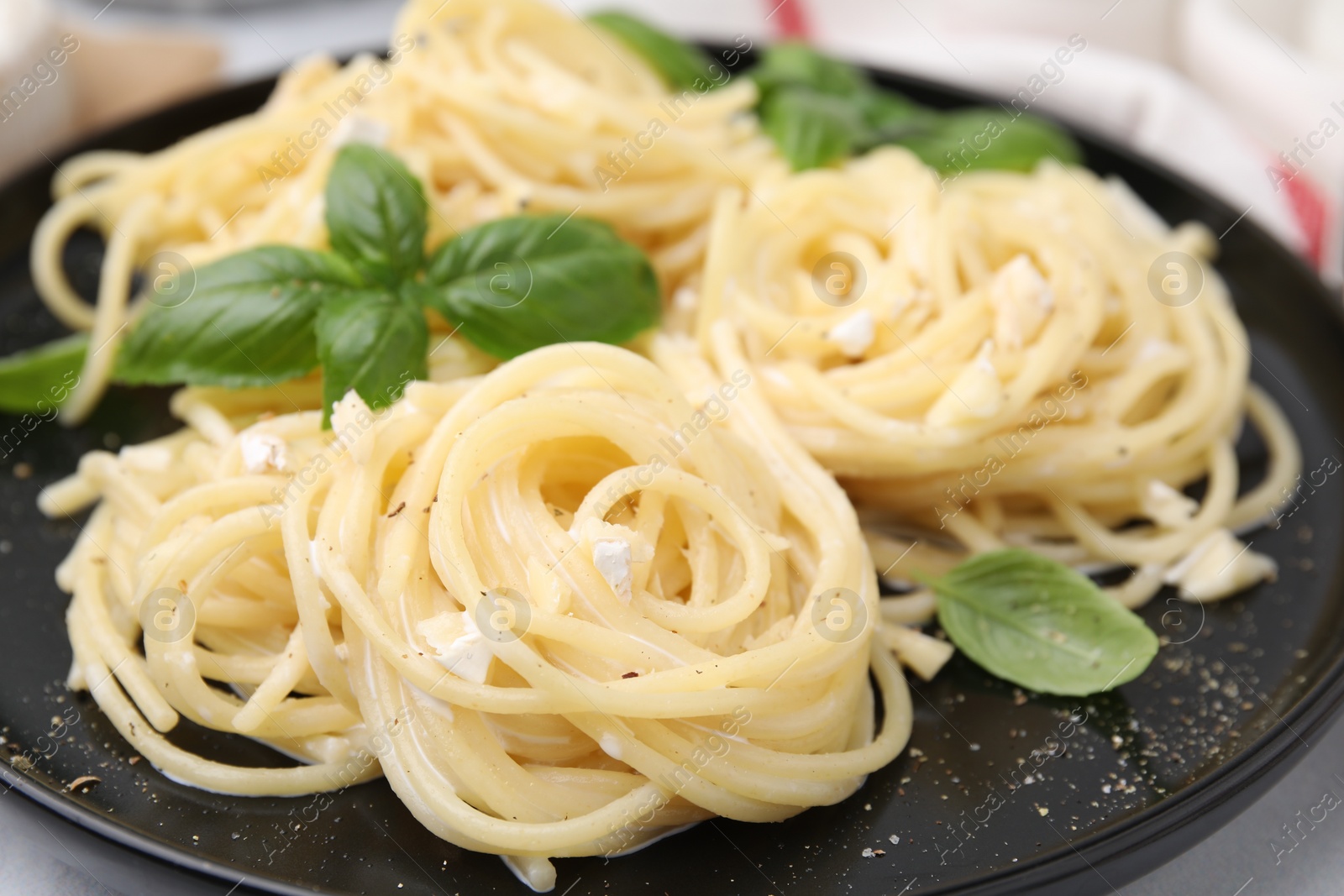 Photo of Delicious pasta with brie cheese and basil leaves on white table, closeup