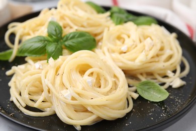 Delicious pasta with brie cheese and basil leaves on white table, closeup