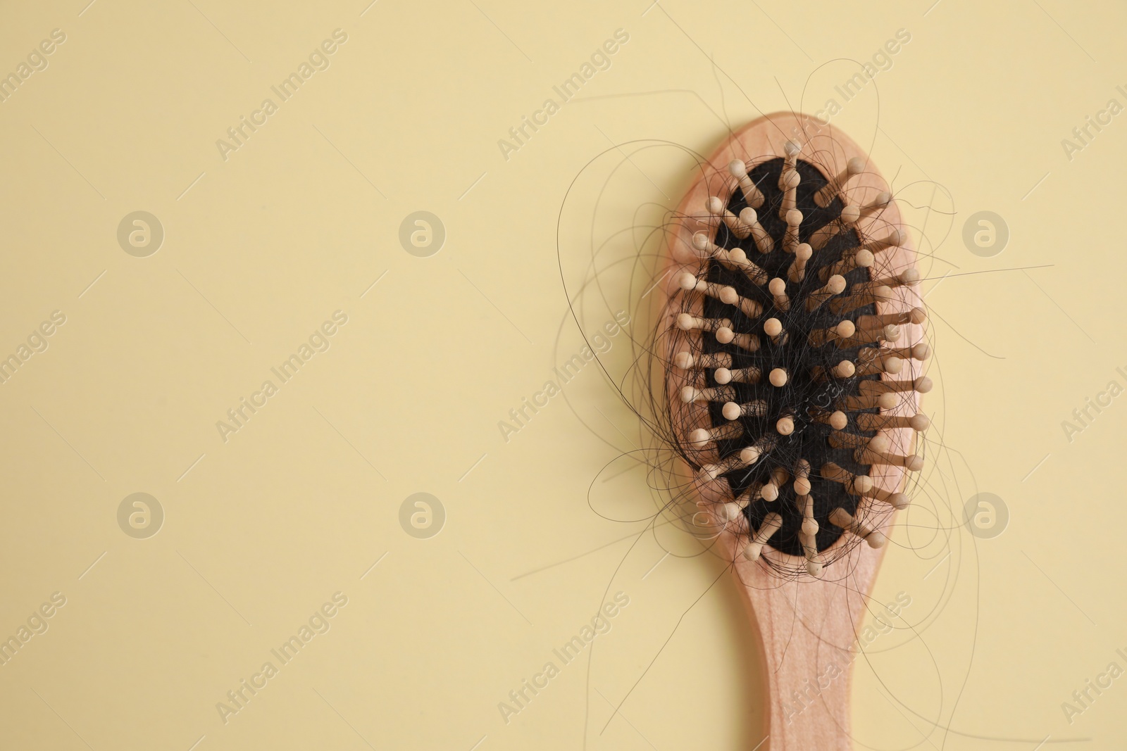 Photo of Wooden brush with lost hair on beige background, top view. Space for text