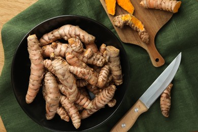 Photo of Many raw turmeric roots and knife on table, flat lay