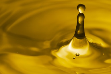 Splash of golden oily liquid with drops as background, closeup. Space for text