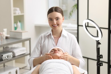 Photo of Cosmetologist making face massage to client in clinic