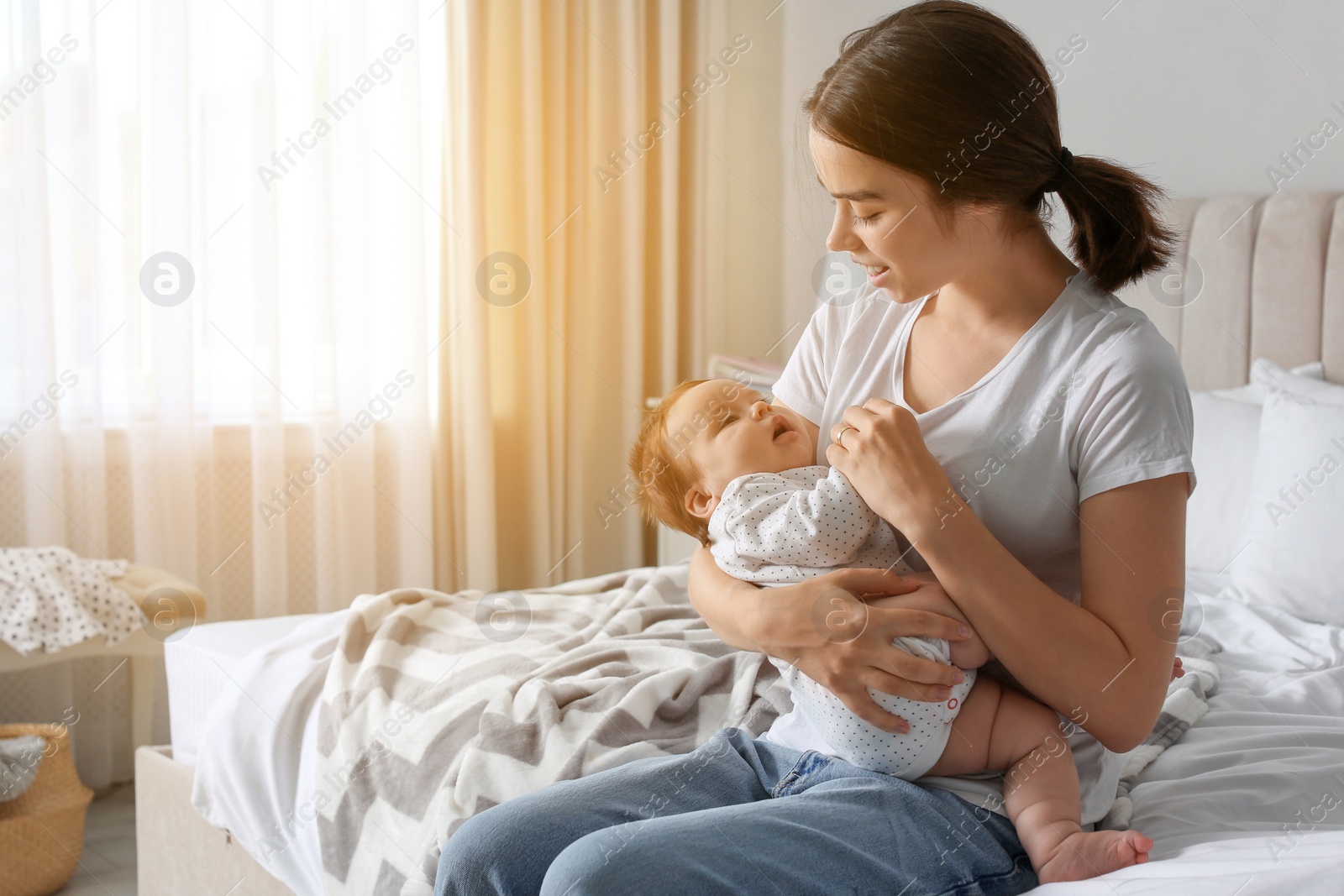 Photo of Young woman with her little baby on bed at home