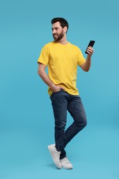 Photo of Handsome man with smartphone on light blue background