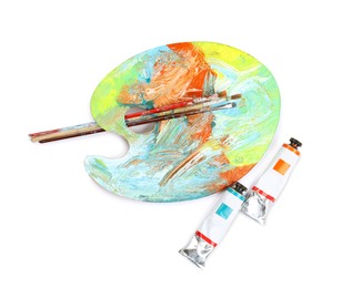 Photo of Dirty artist's palette with brushes and tubes of paint on white background