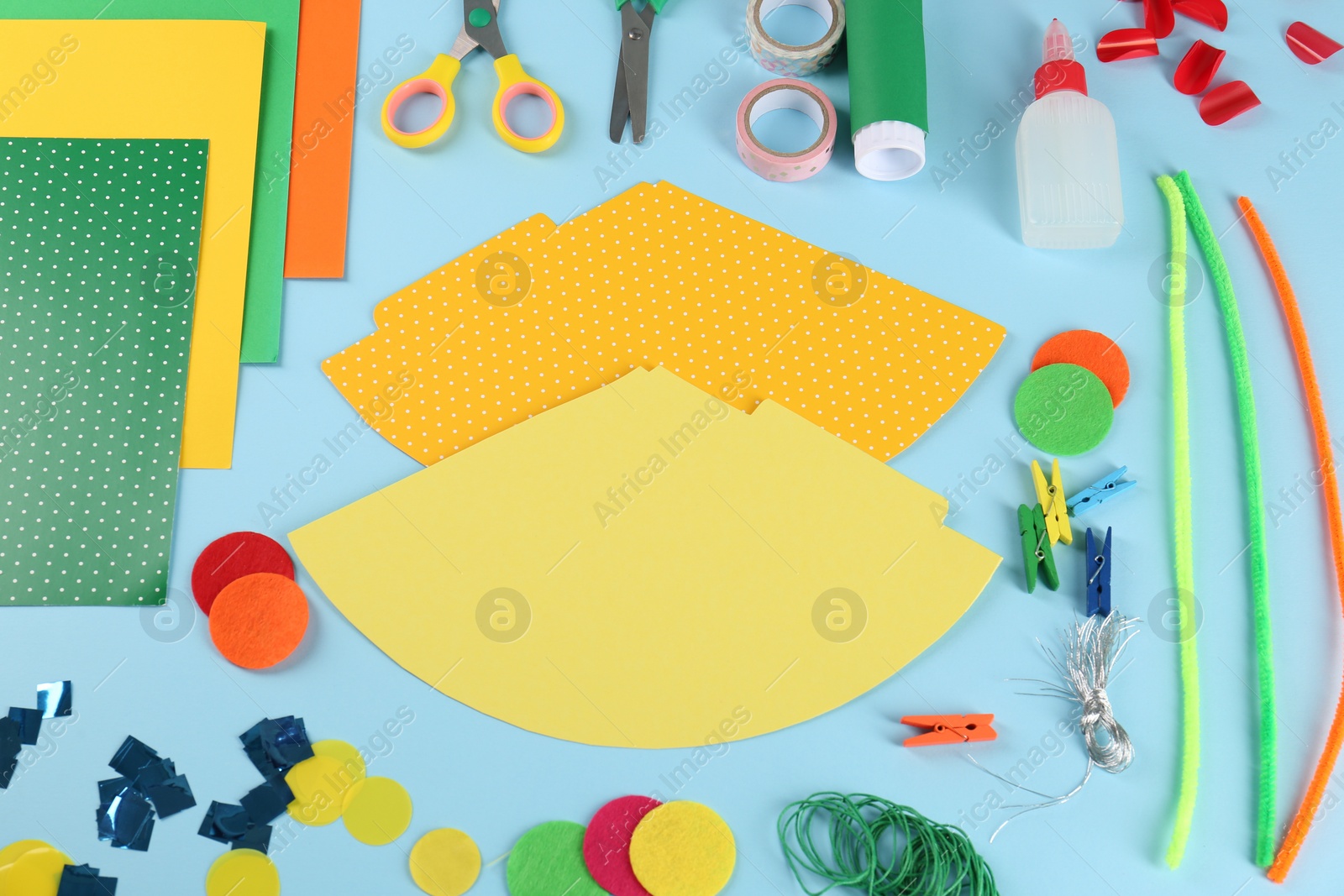 Photo of Flat lay composition with different materials to create party hats on light blue background. Handmade decoration