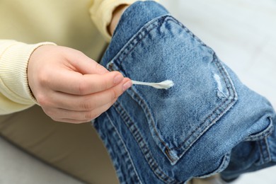 Photo of Woman removing chewing gum from jeans, closeup