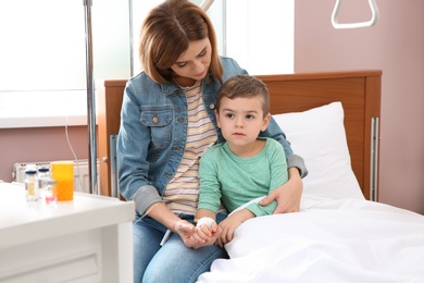 Woman visiting her little child with intravenous drip in hospital