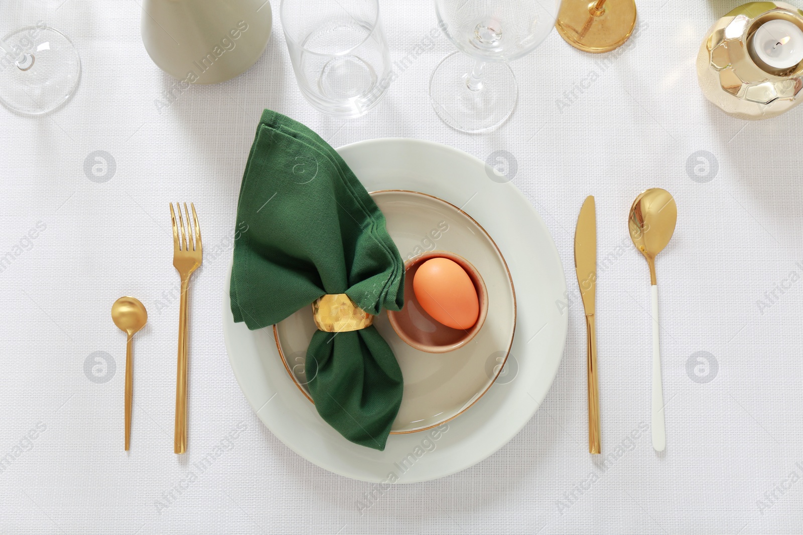 Photo of Festive Easter table setting with painted egg and burning candle, flat lay