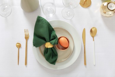 Festive Easter table setting with painted egg and burning candle, flat lay