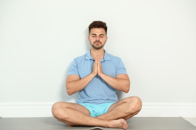 Photo of Young man practicing zen yoga near wall indoors