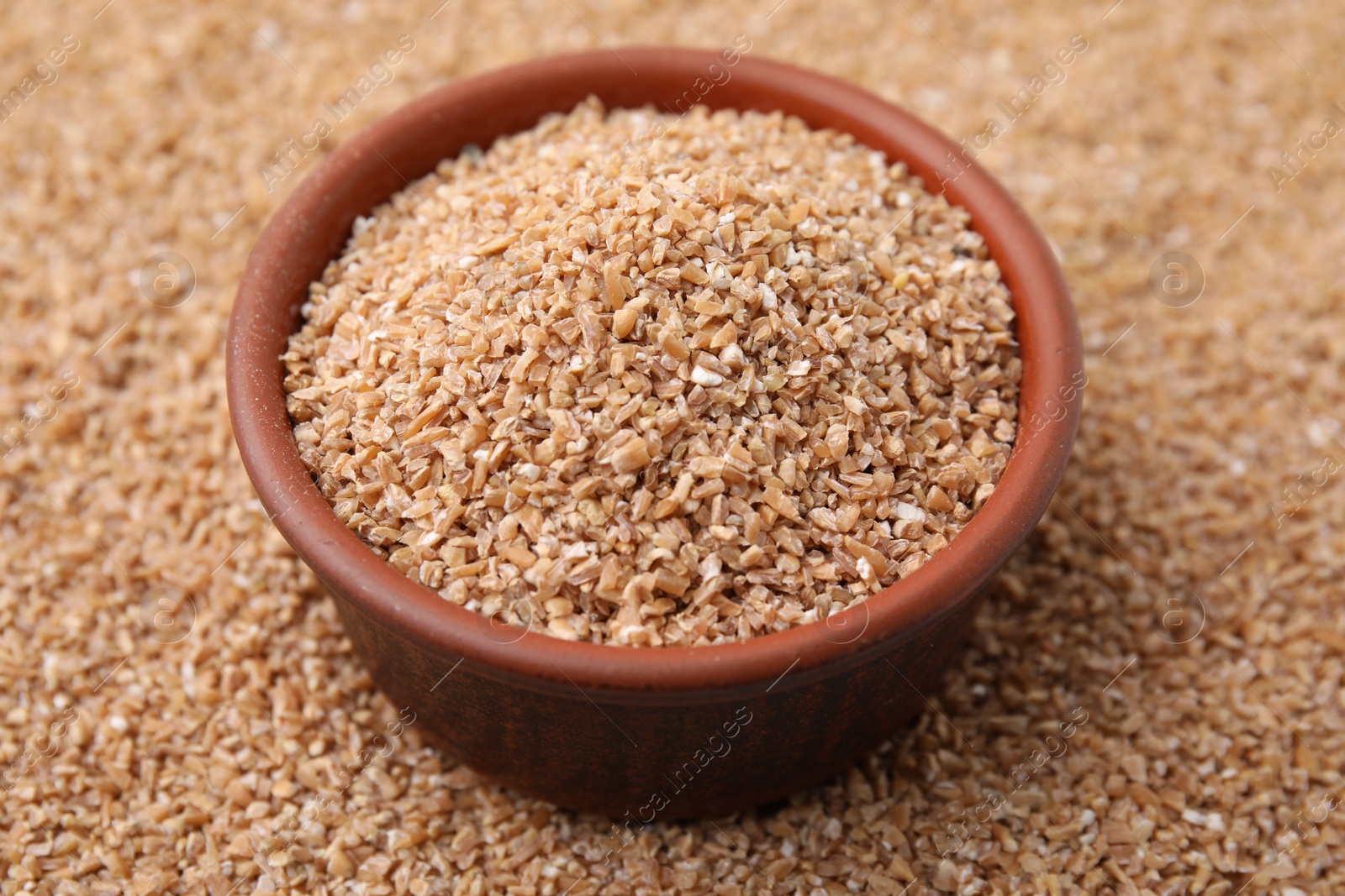 Photo of Bowl and dry wheat groats, closeup view