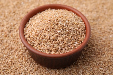 Bowl and dry wheat groats, closeup view