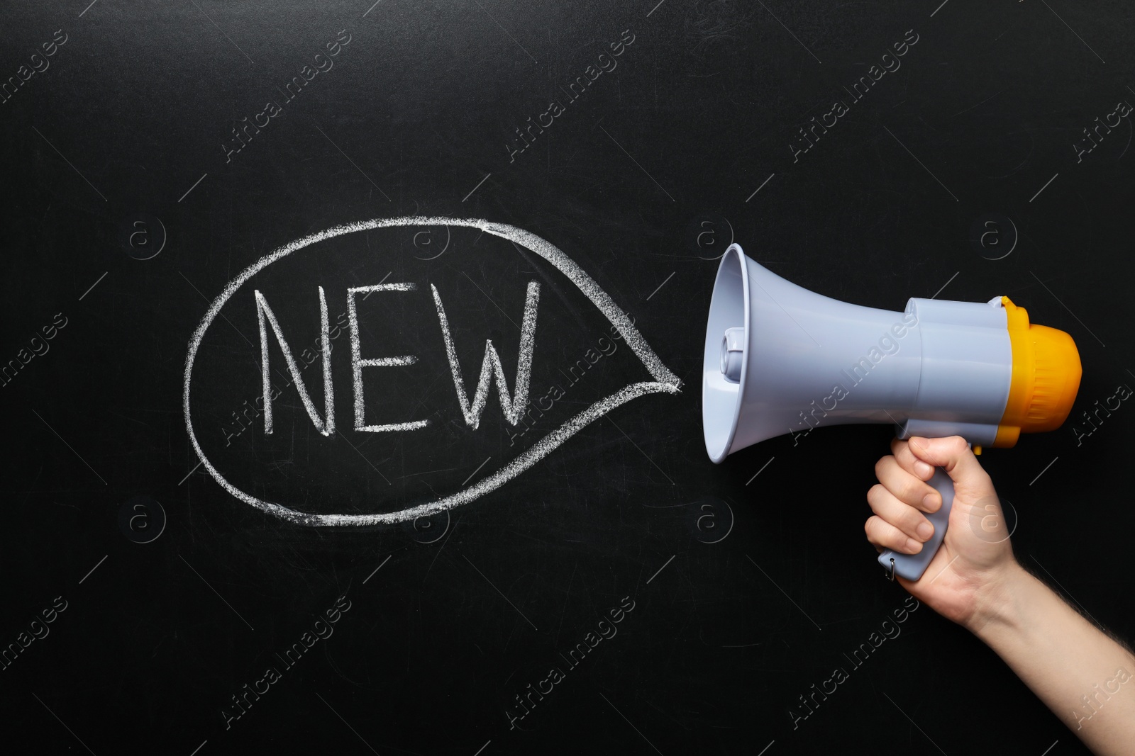 Photo of Man holding megaphone and word NEW on chalkboard