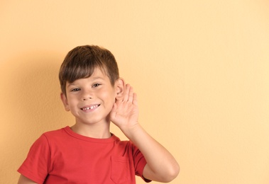 Cute little boy with hearing problem on color background. Space for text