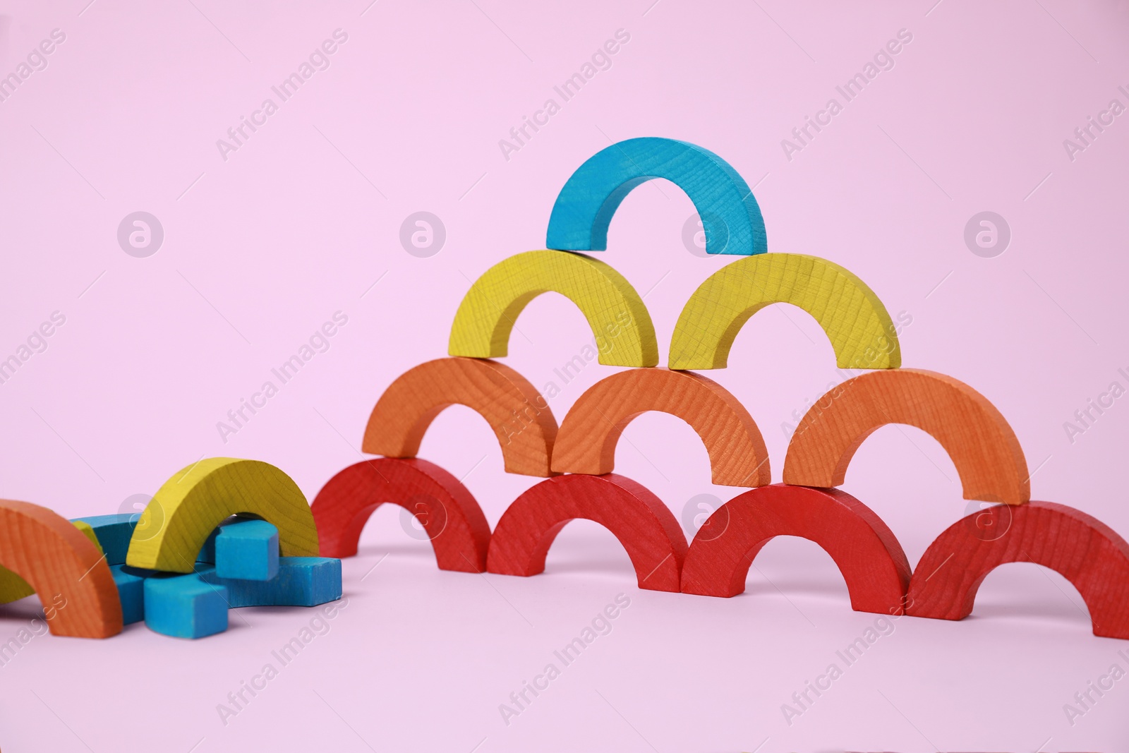 Photo of Colorful wooden pieces of playing set on pink background. Educational toy for motor skills development