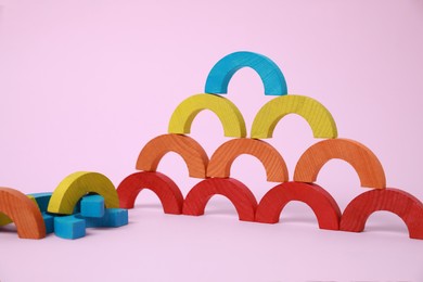 Photo of Colorful wooden pieces of playing set on pink background. Educational toy for motor skills development