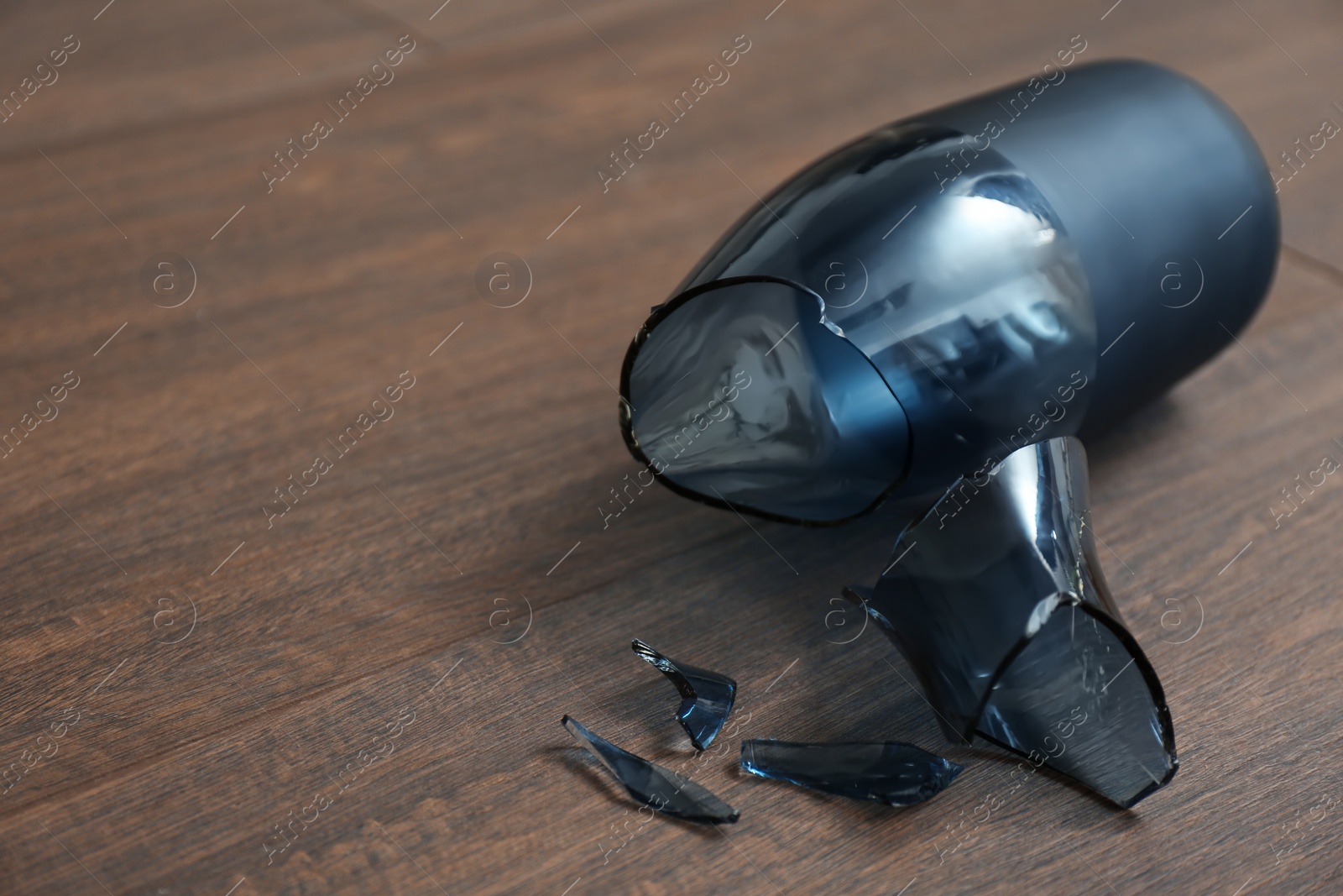 Photo of Broken blue glass vase on wooden floor, closeup. Space for text