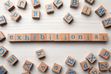 Photo of Word EXHIBITIONIST made with wooden cubes on white table, flat lay