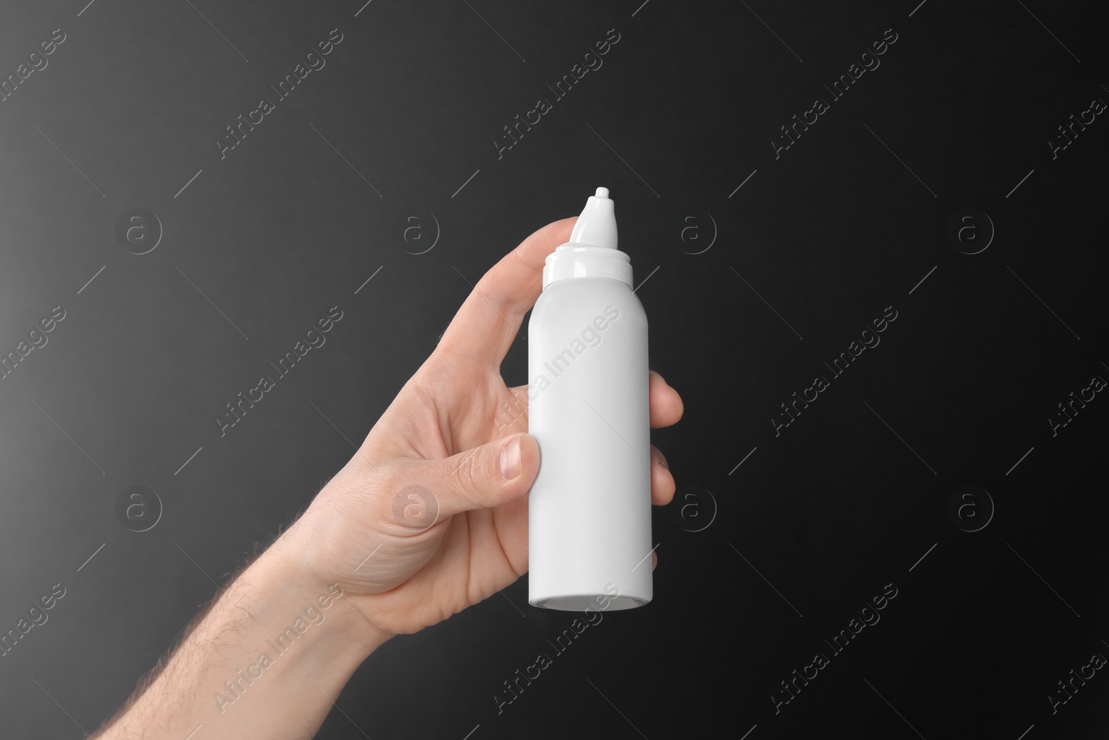 Photo of Man holding nasal spray on black background, closeup