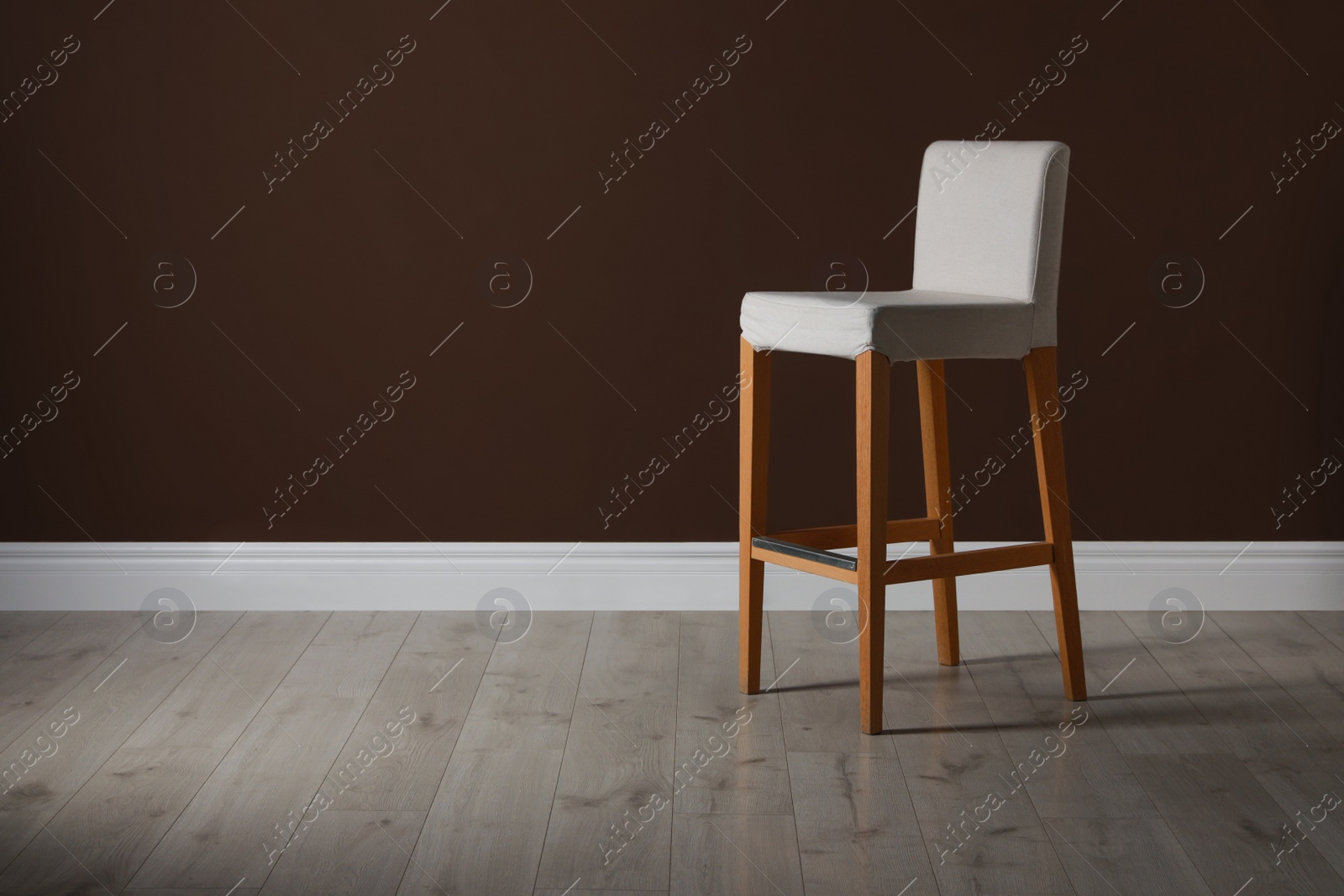 Photo of Stylish bar stool near brown wall indoors. Space for text