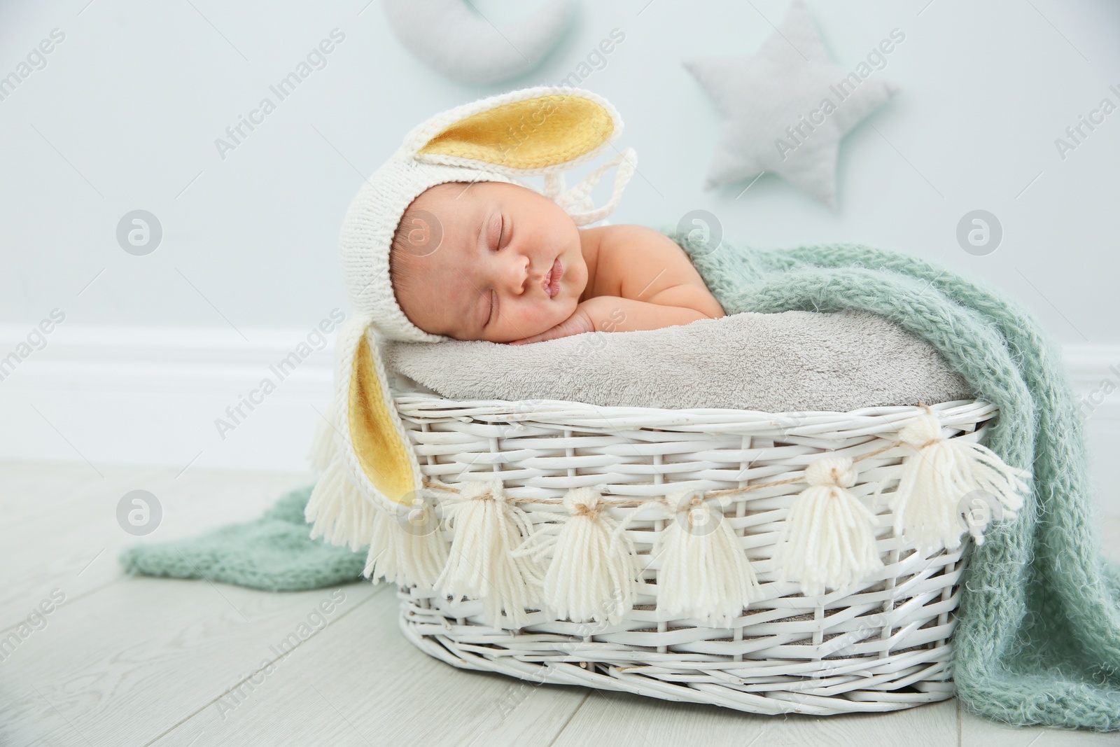 Photo of Adorable newborn child wearing bunny ears hat in baby nest indoors