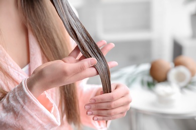 Young woman applying mask onto hair at home