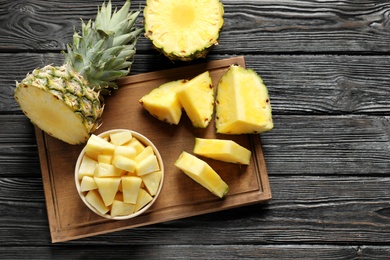 Wooden board with fresh sliced pineapple on table, top view