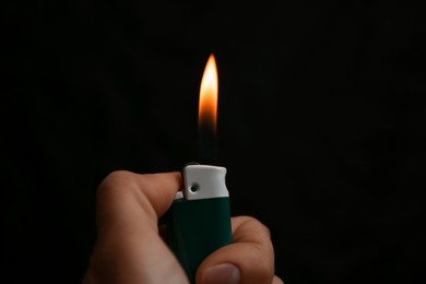 Photo of Woman holding lighter on black background, closeup