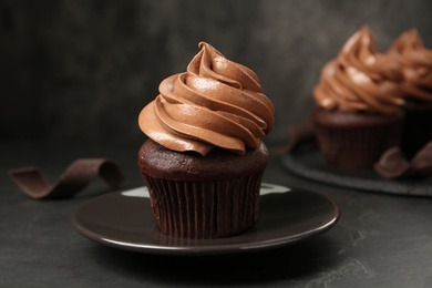 Photo of Delicious fresh chocolate cupcake on black slate table, closeup