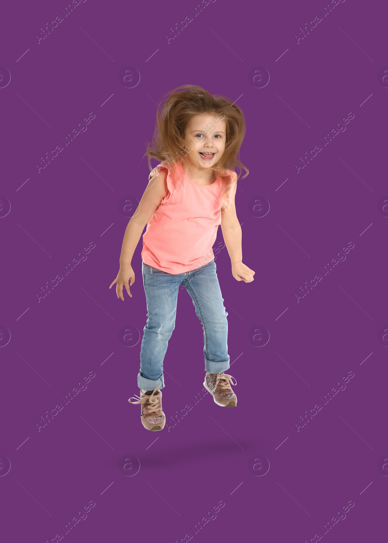 Image of Happy cute girl jumping on purple background