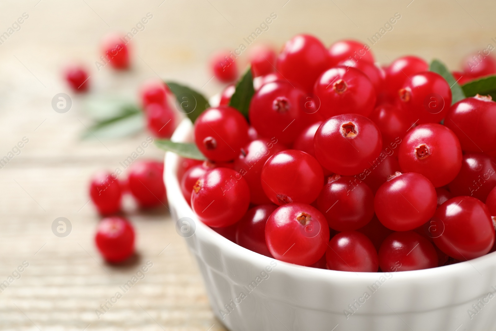 Photo of Bowl with tasty ripe cranberries on table, closeup