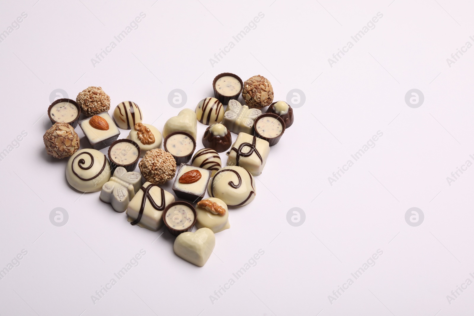 Photo of Heart made with delicious chocolate candies on white background