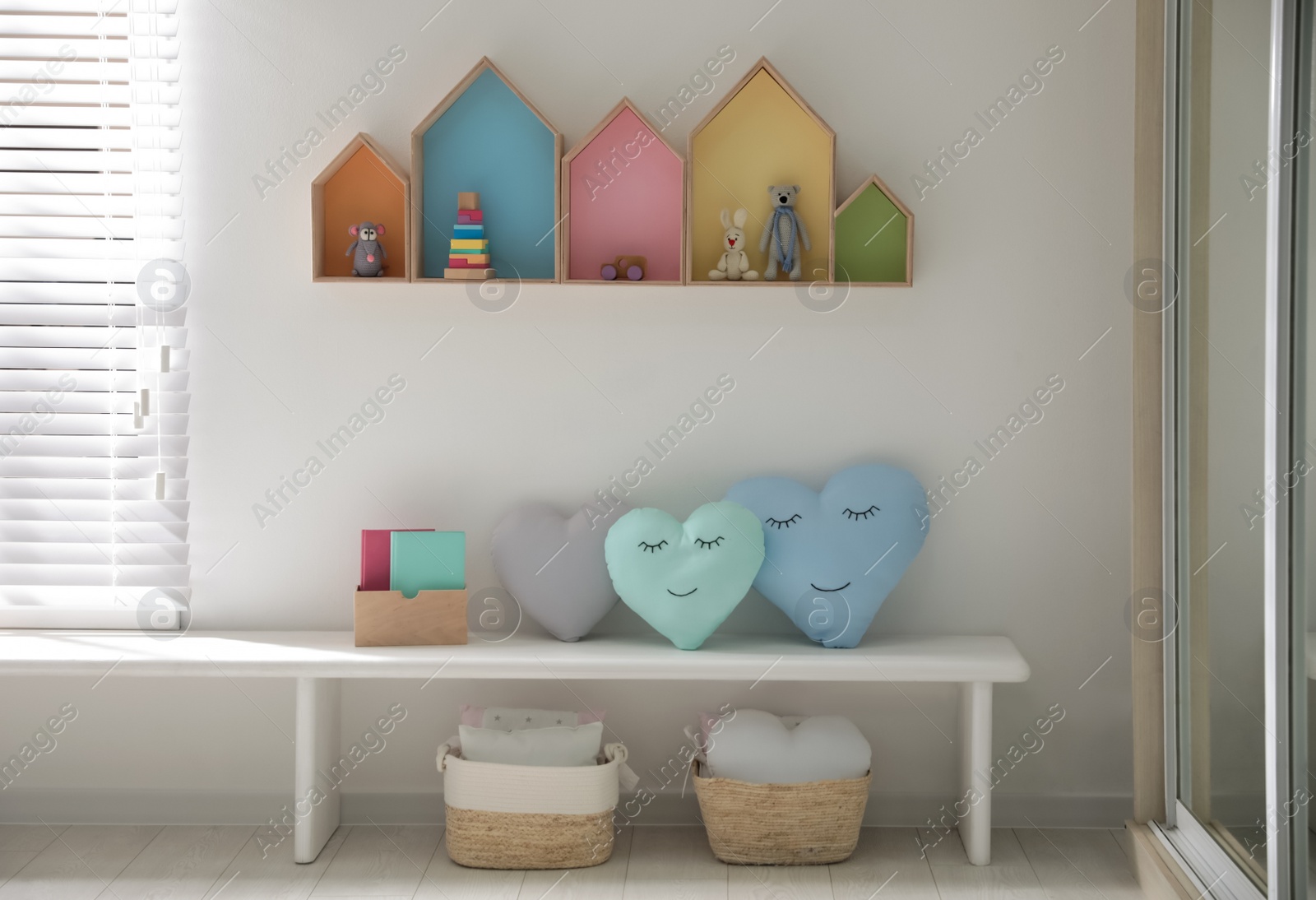 Photo of Cute children's room interior design with house shaped shelves on white wall and bench