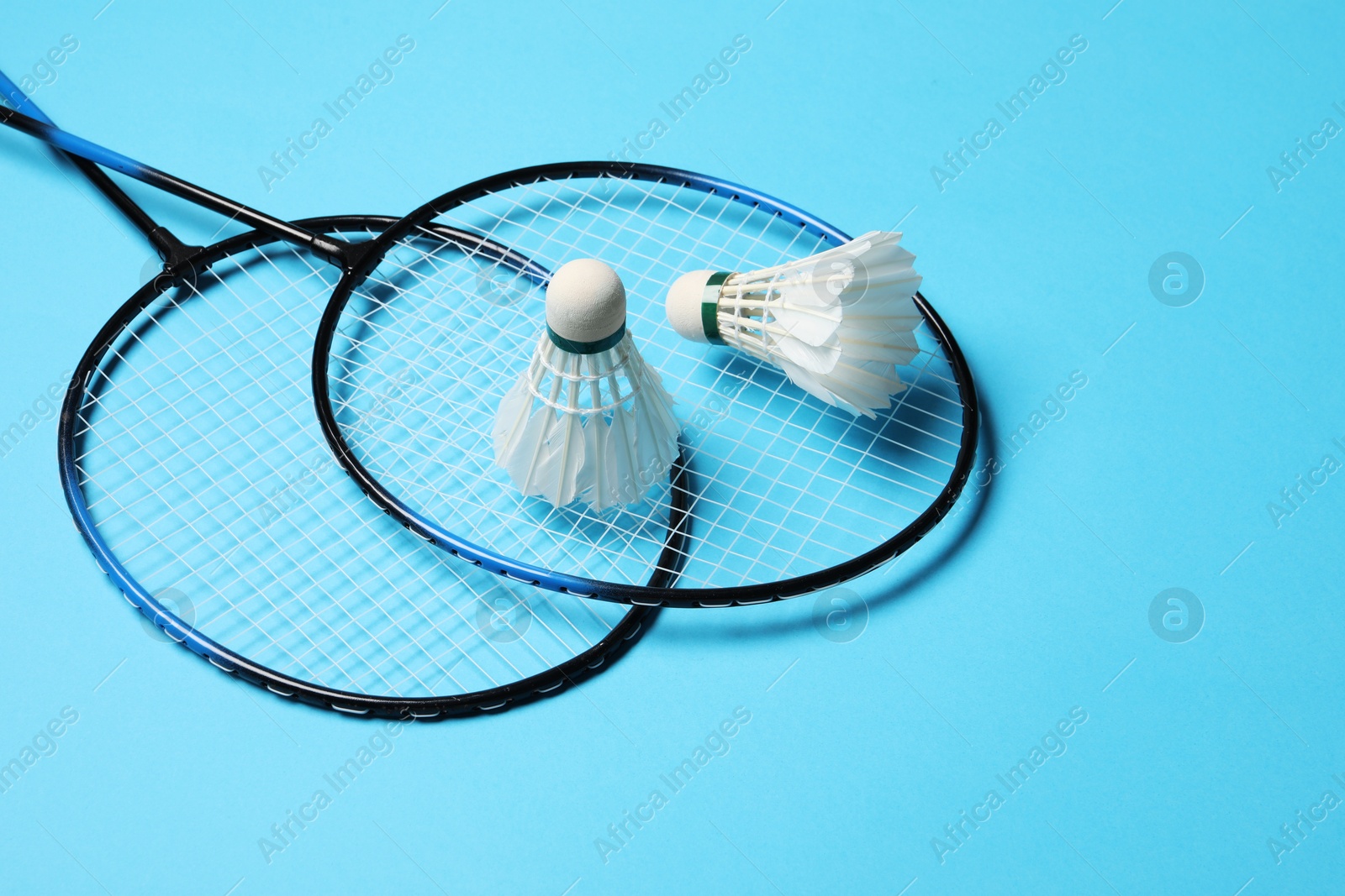Photo of Feather badminton shuttlecocks and rackets on light blue background
