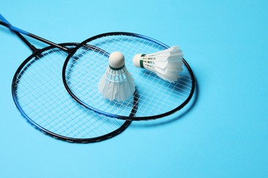 Photo of Feather badminton shuttlecocks and rackets on light blue background